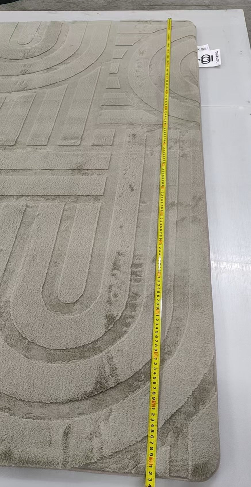 Textured gray mat with a measuring tape for scale on a white background