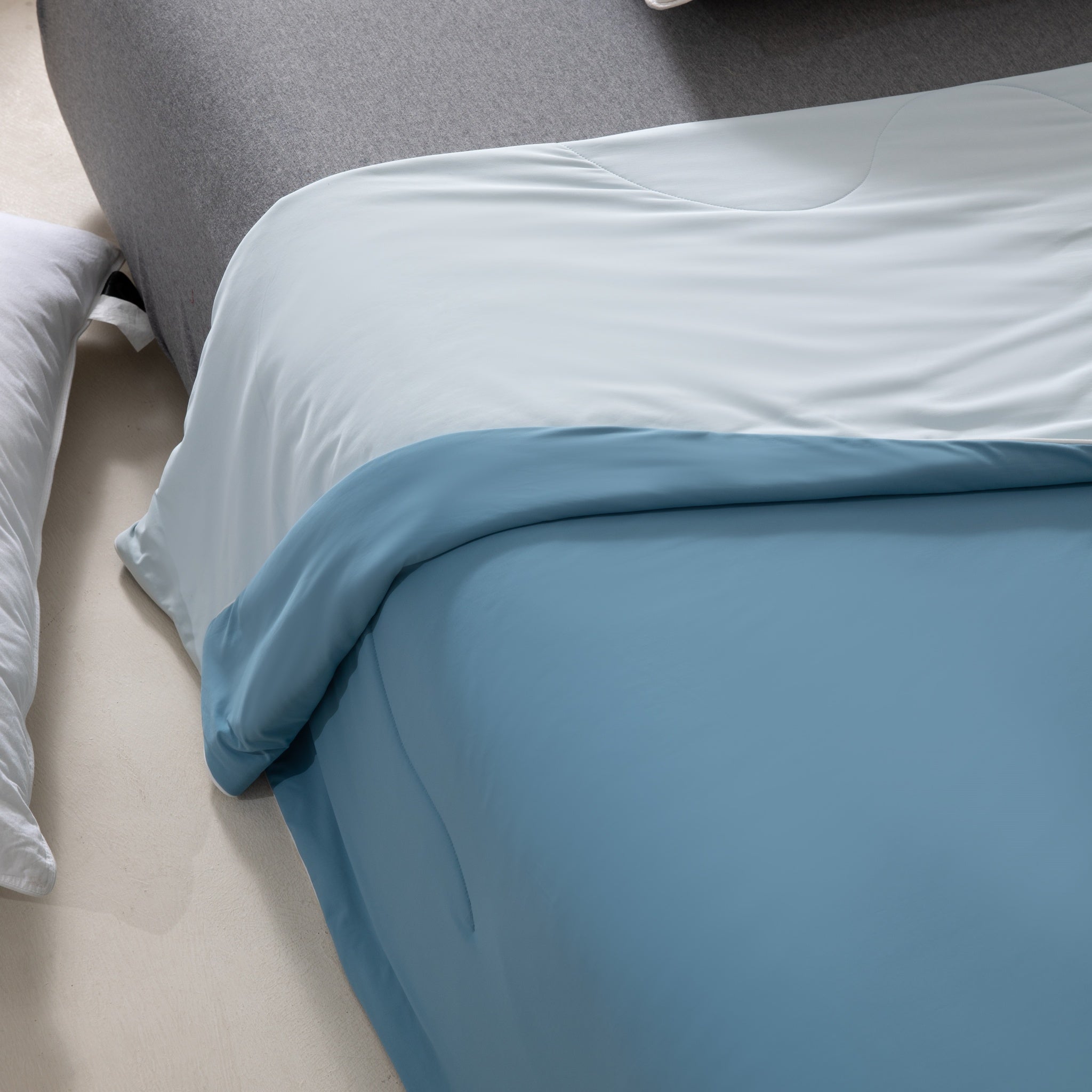 Close-up of a bed with blue bedding and gray headboard