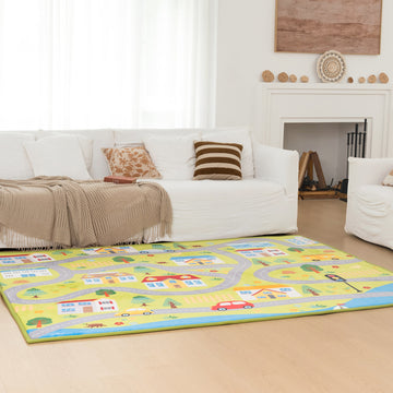 Living room with a colorful rug featuring roads and houses, a white sofa with pillows, and a fireplace.