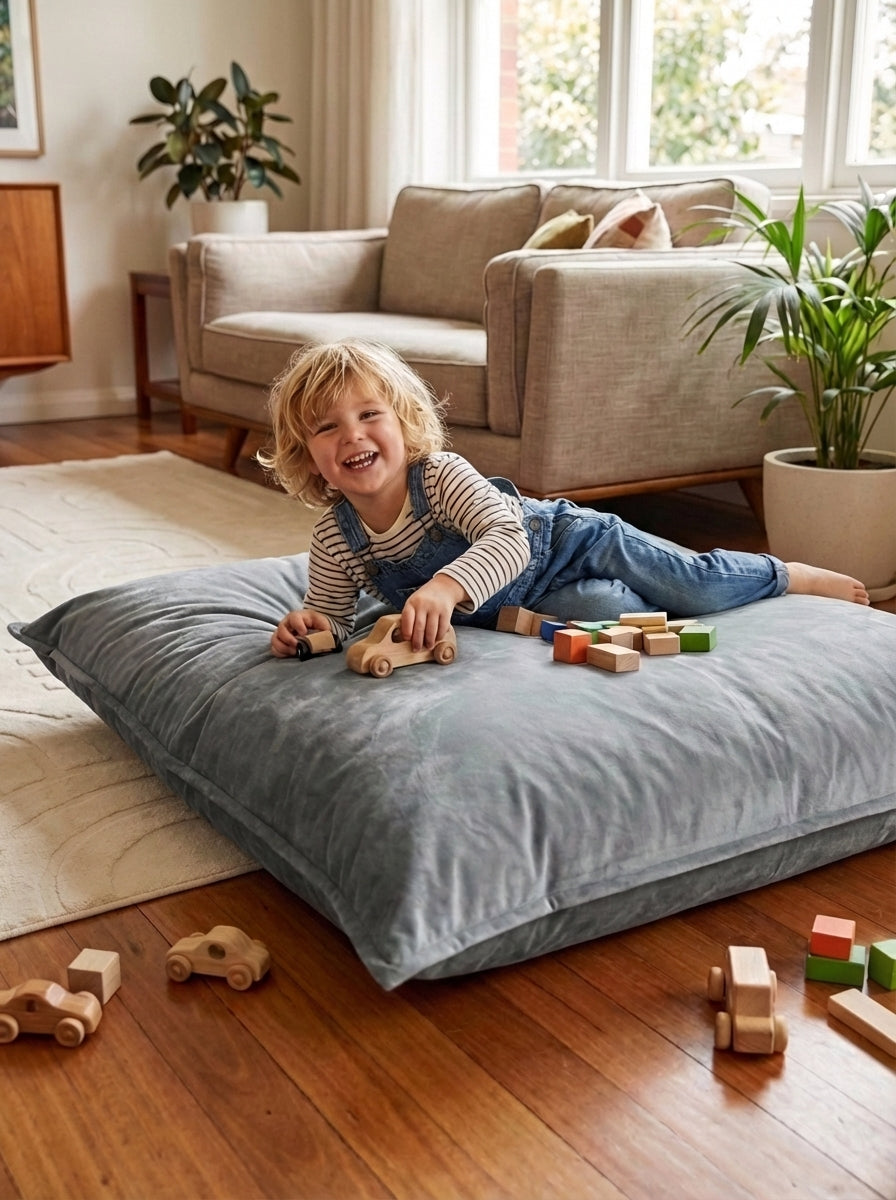 Child playing with toys on a large pillow in a living room.