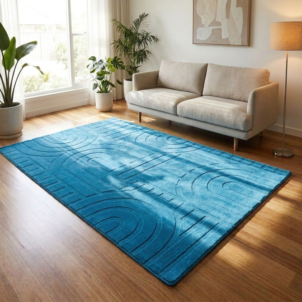 Blue area rug on a wooden floor in a living room with a sofa and plants.