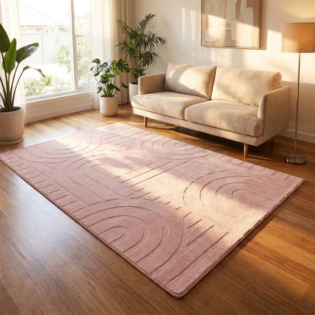 Living room with a pink rug, beige sofa, and plants.