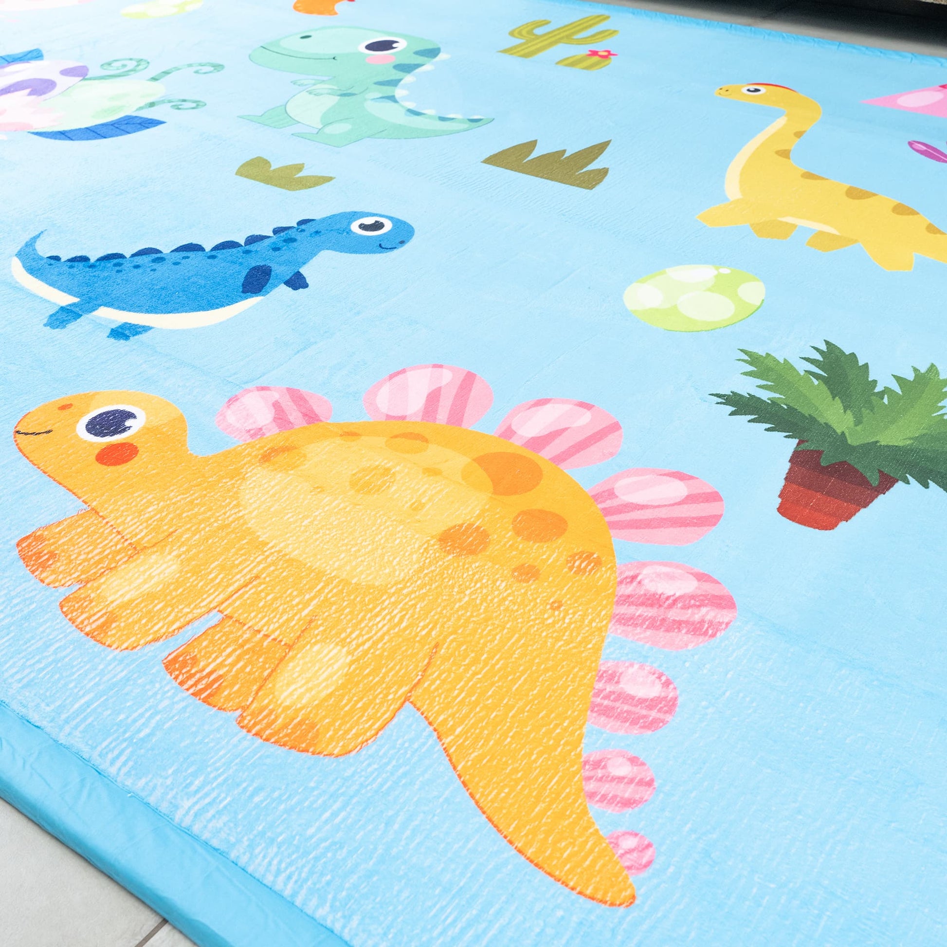 Children's play mat with colorful dinosaur illustrations on a blue background