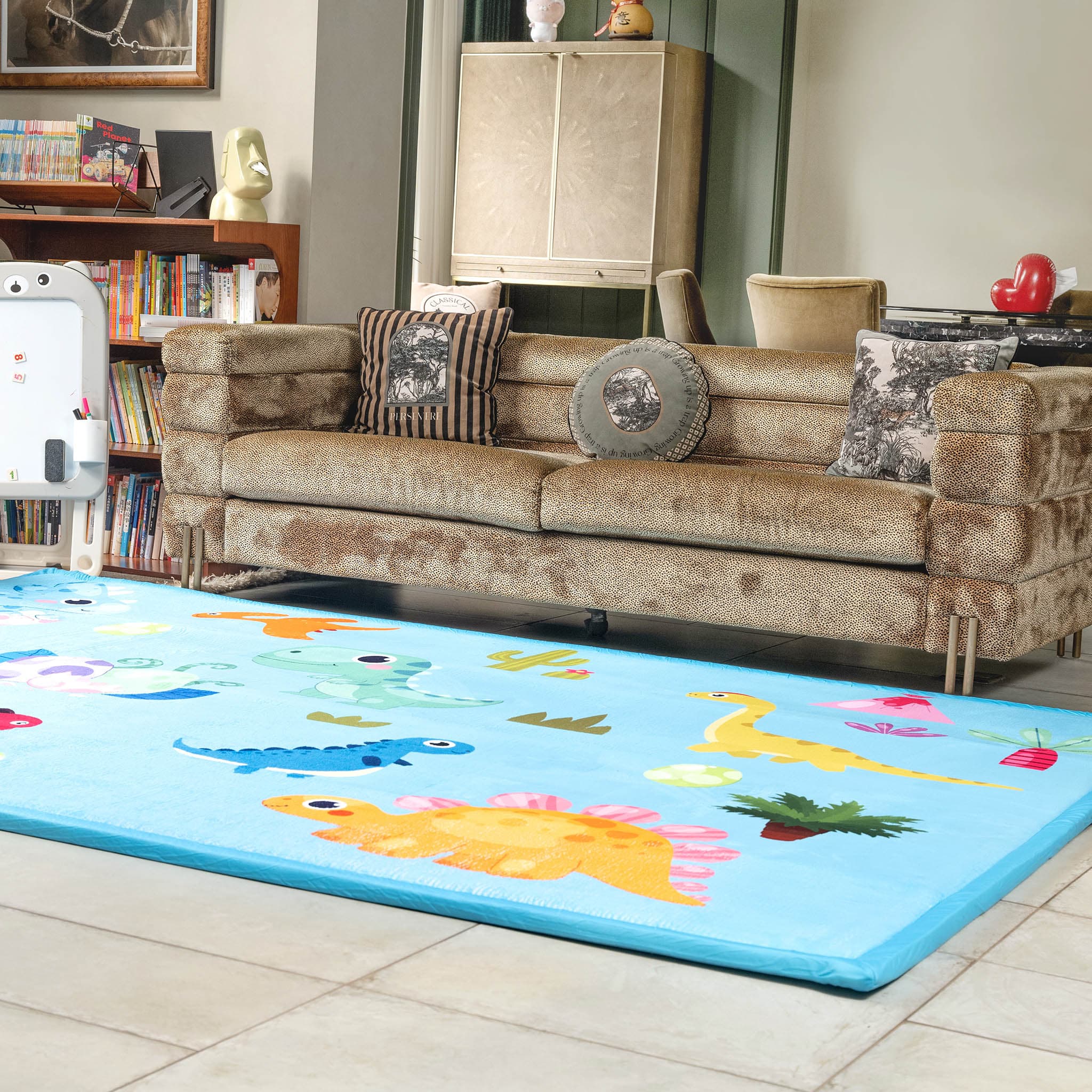 Living room with a brown sofa and a colorful LuxKing dinosaur Cloud Mat on the floor.
