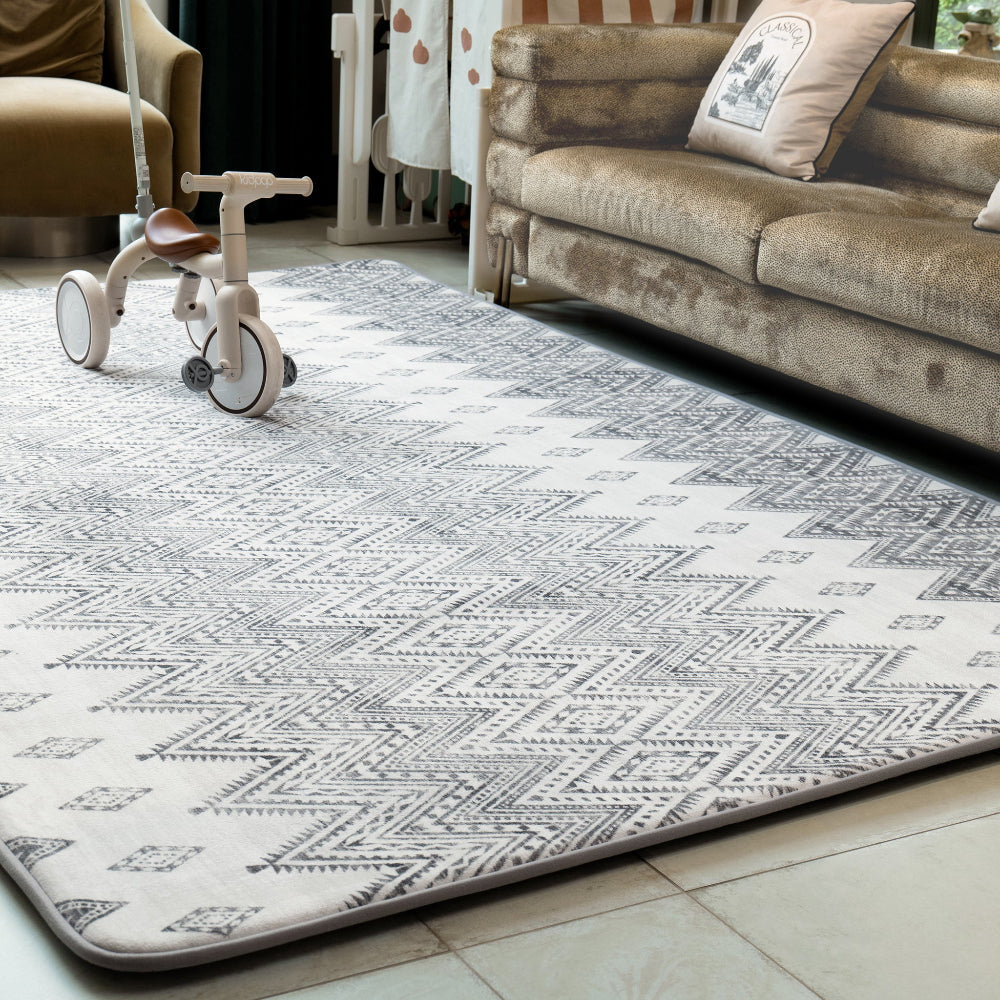 Patterned rug on a floor with a sofa and tricycle in the background