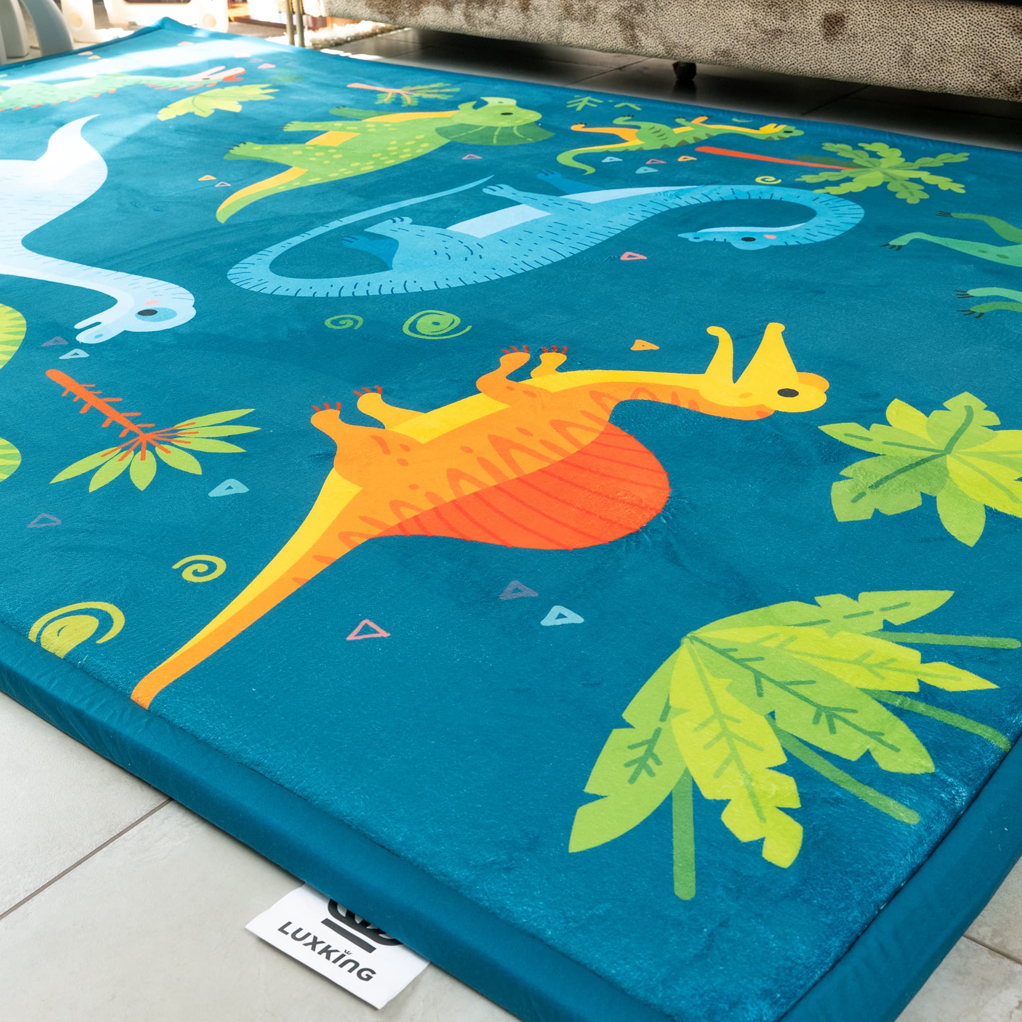 Colorful dinosaur-themed play mat with a Luxking label on a tiled floor.
