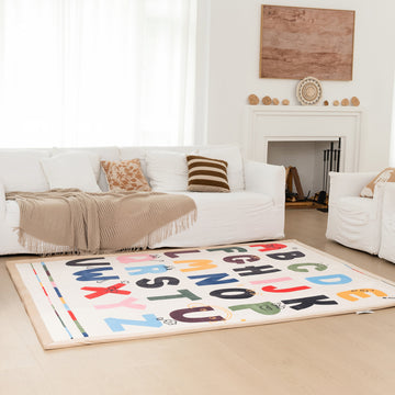 Living room with a white sofa, alphabet rug, and decorative items.