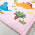 Children's play mat with colorful dinosaur and plant designs on a pink border.