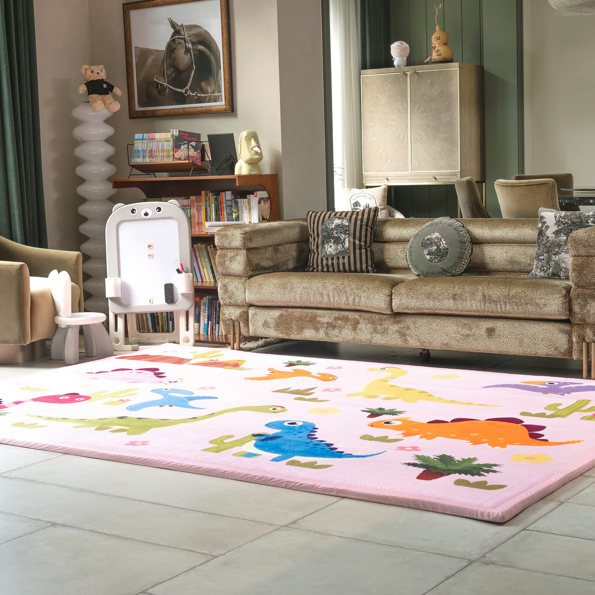 Children's room with a dinosaur rug on the floor, a sofa with cushions, and books on shelves.