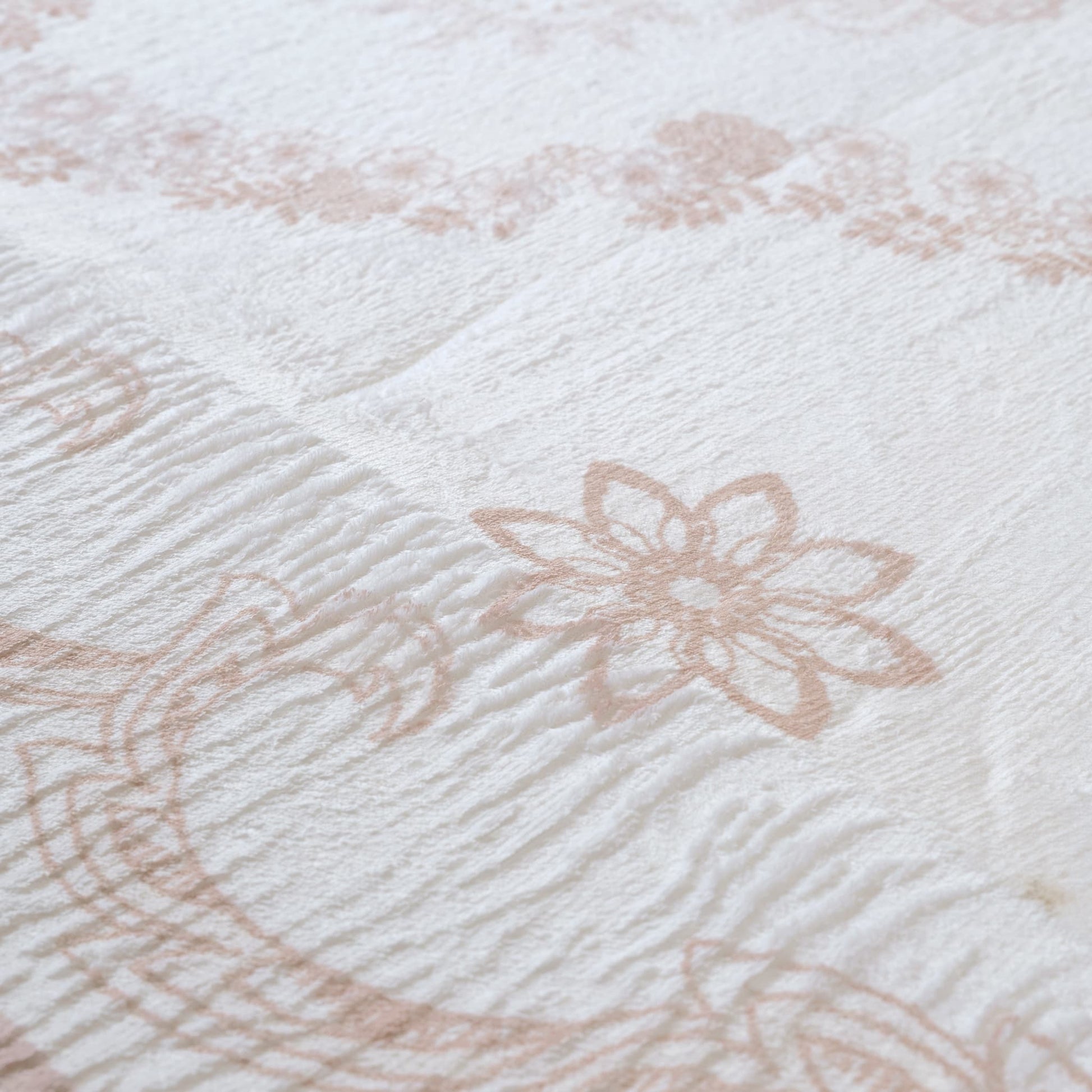 Close-up of textured fabric with floral patterns in beige on a white background