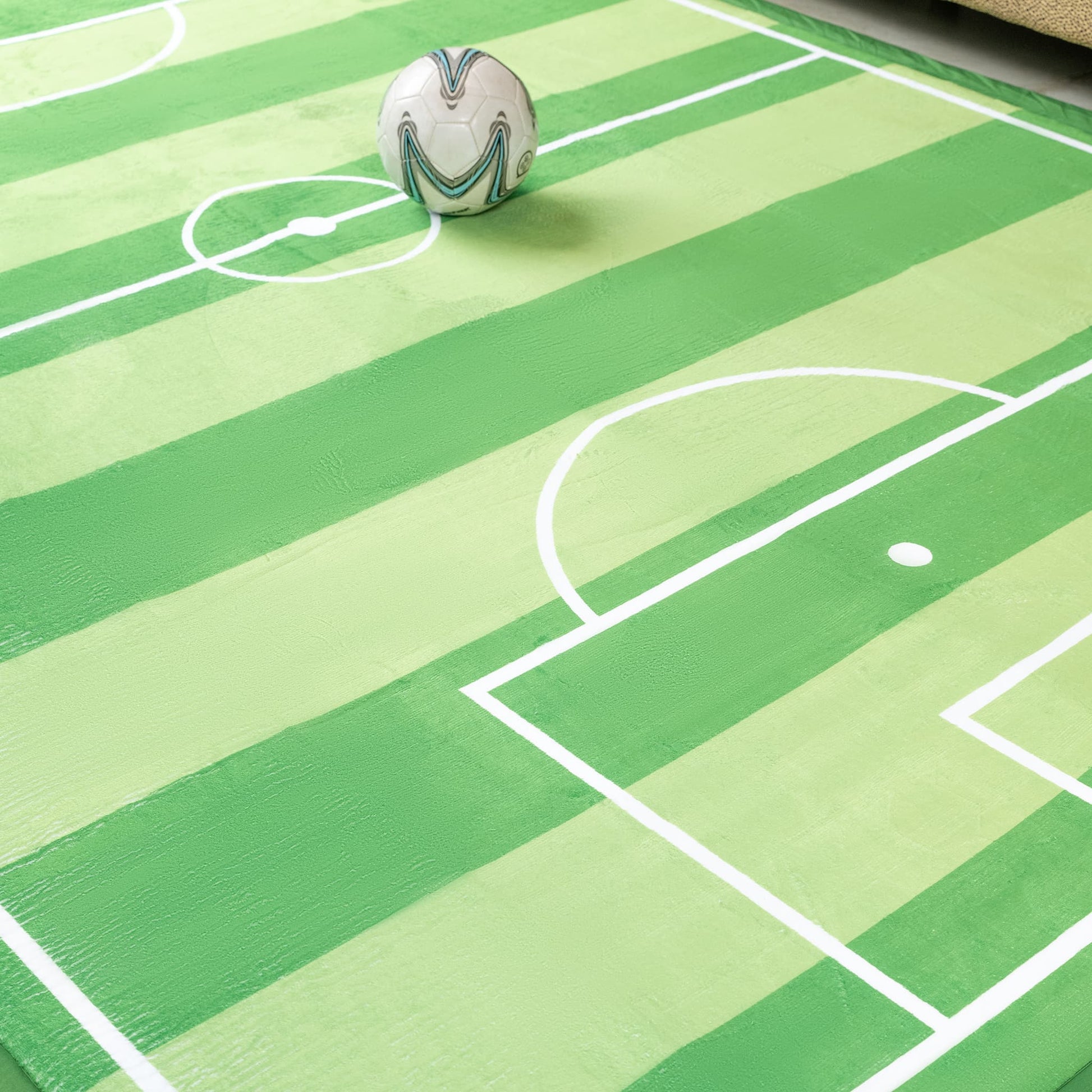 Soccer ball on a green sports-themed play mat with white lines