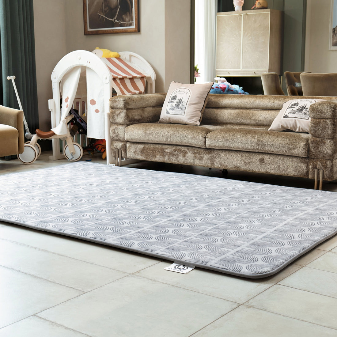 Living room with a patterned rug on the floor, sofa, and baby chair.