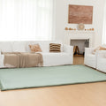 Living room with a green rug, white sofa, and decorative items.