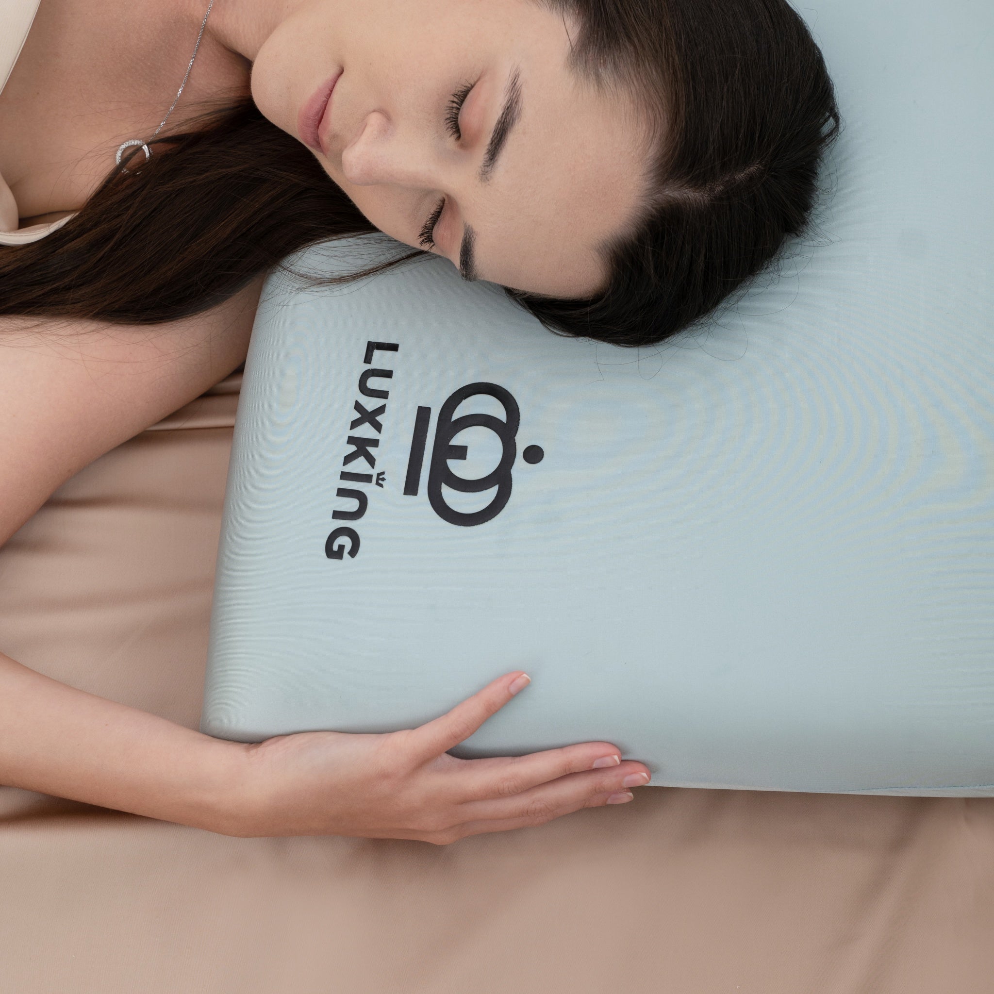 Woman lying on a Luxking branded pillow with a beige blanket.