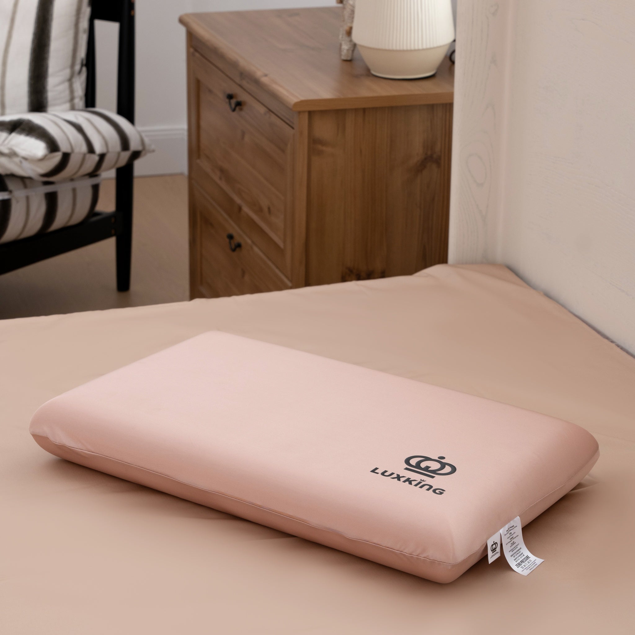 Pink pillow with Luxking logo on a bed in a bedroom setting