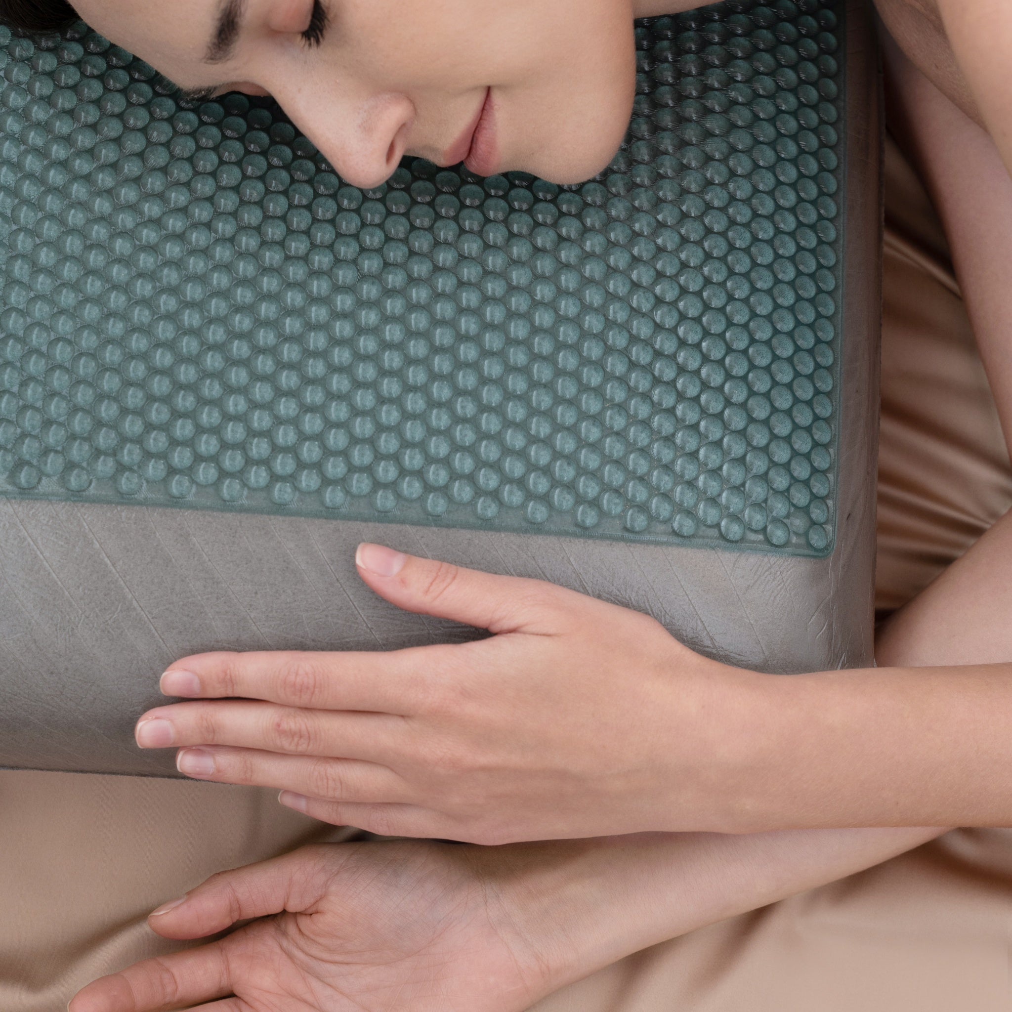 Person lying on a textured green mat with a focus on their hands.