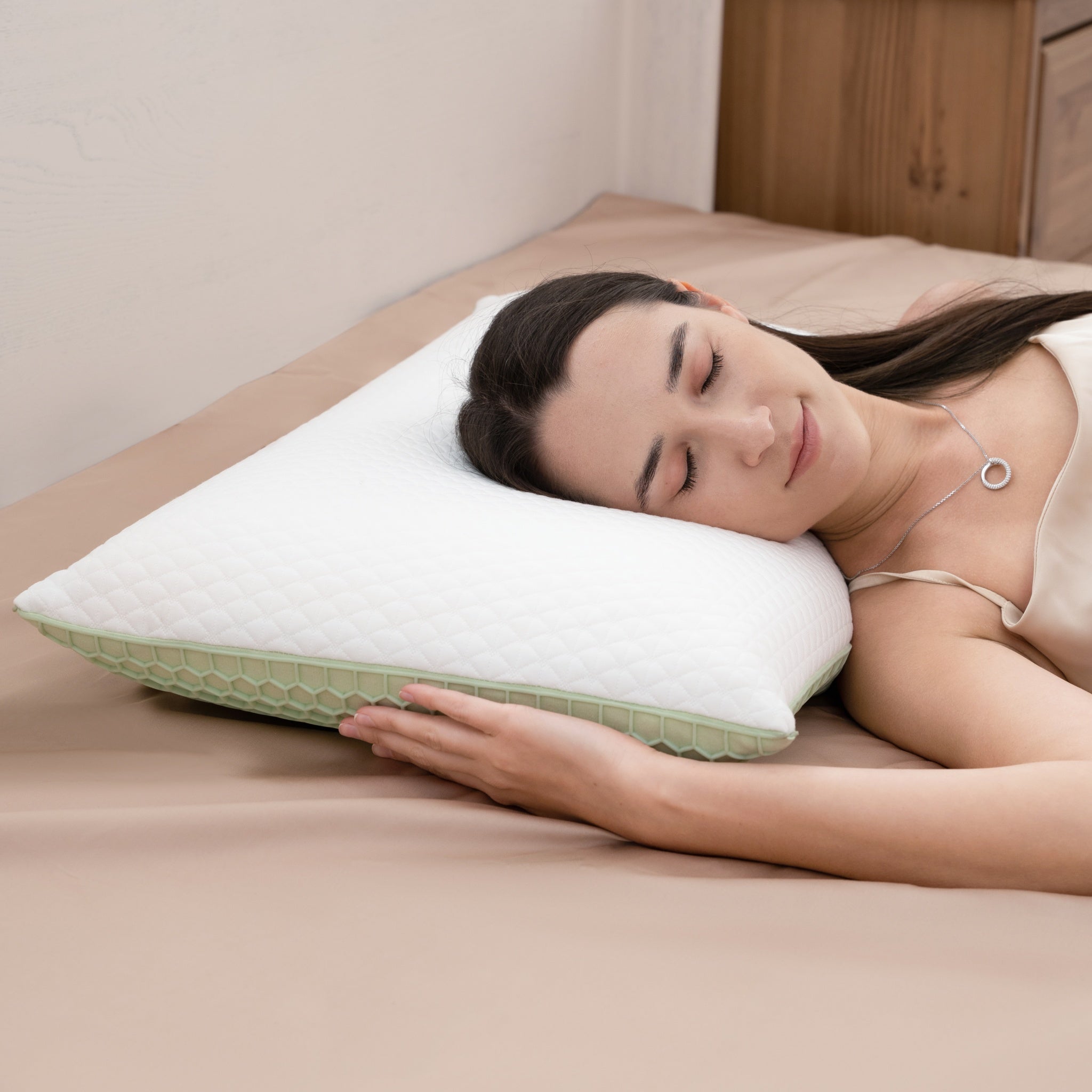 Woman sleeping on a bed with a green and white pillow