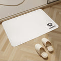 White mat with Luxking logo on a wooden floor with white slippers.