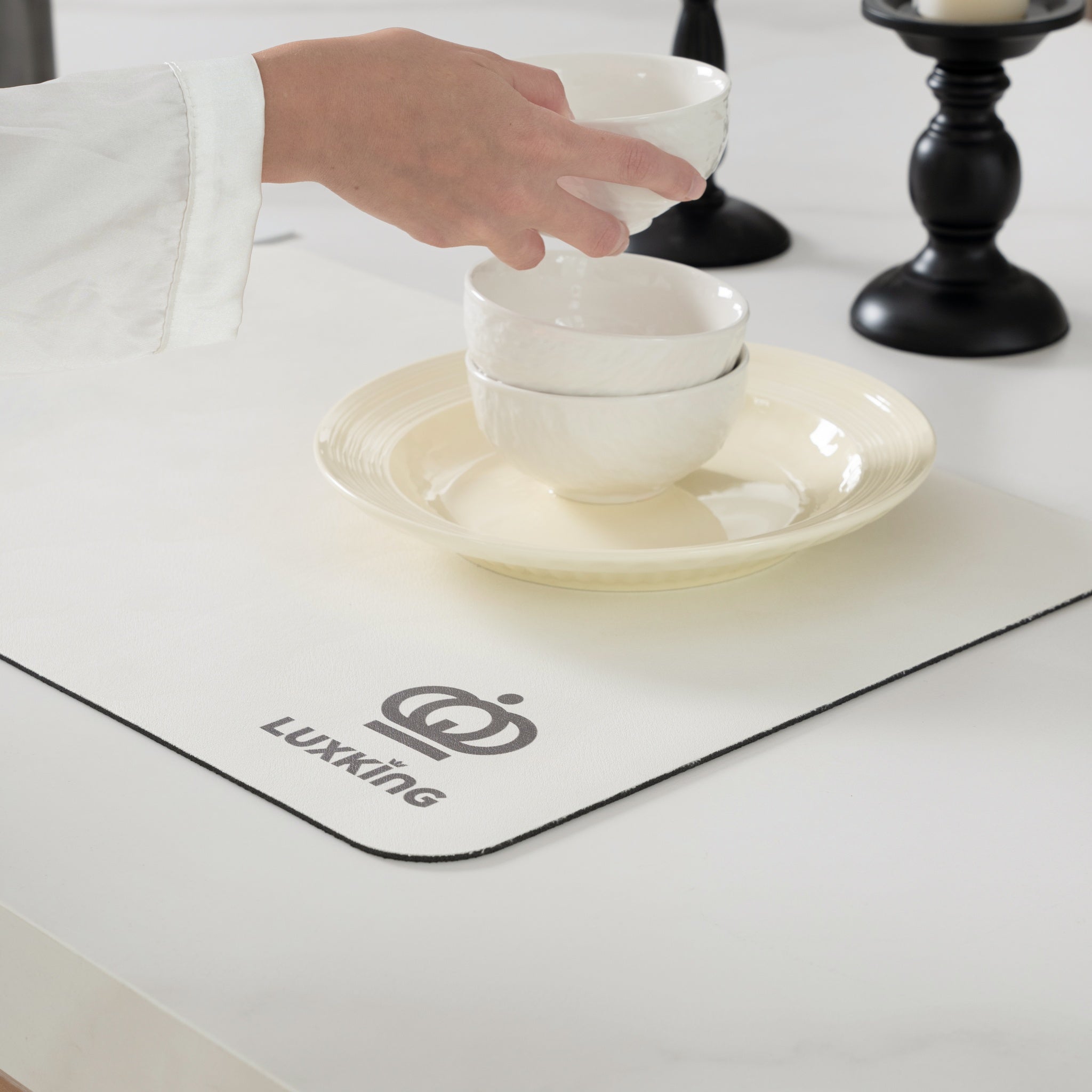 White ceramic bowls being placed on a white plate with Luxking logo on a placemat.