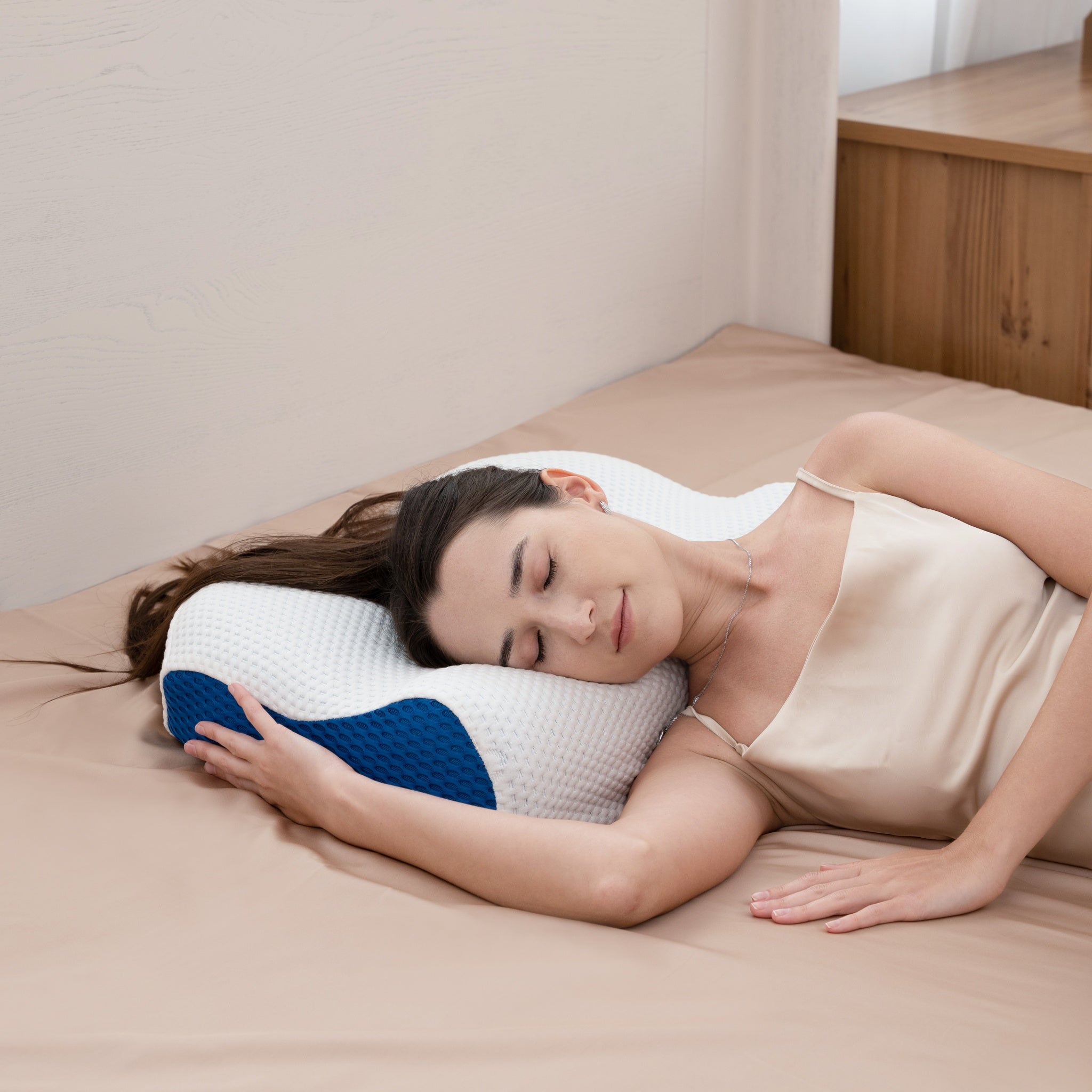 Woman sleeping on a bed with a white pillow featuring blue accents