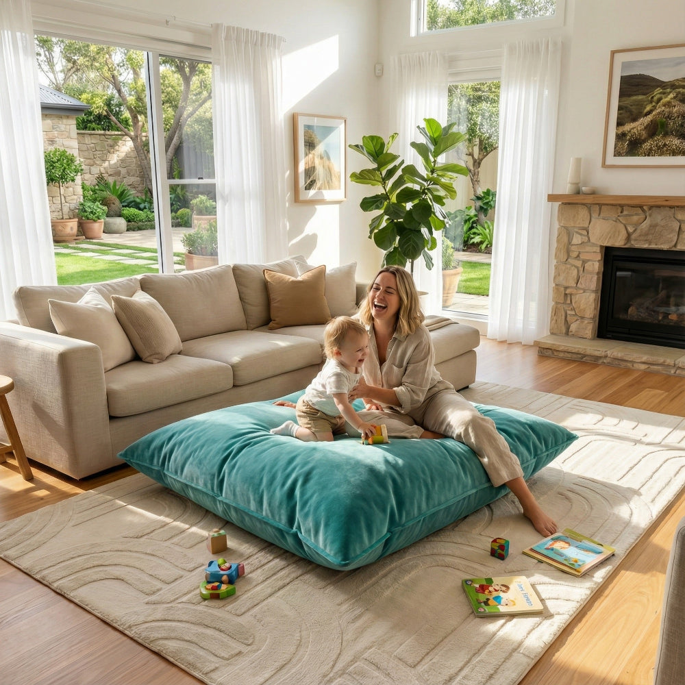 Woman and child playing on a teal pillow in a bright living room.