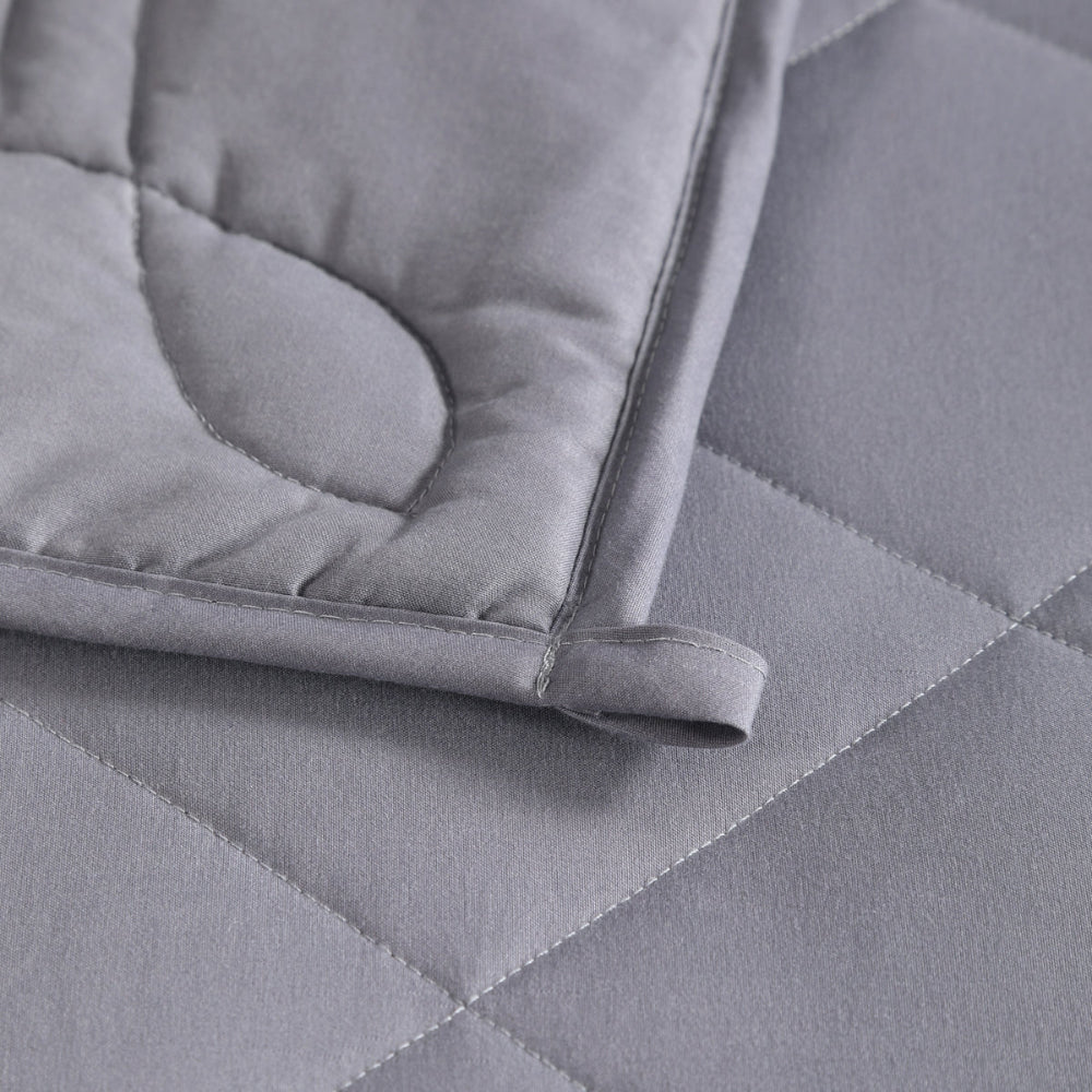Close-up of a gray quilted comforter on a bed