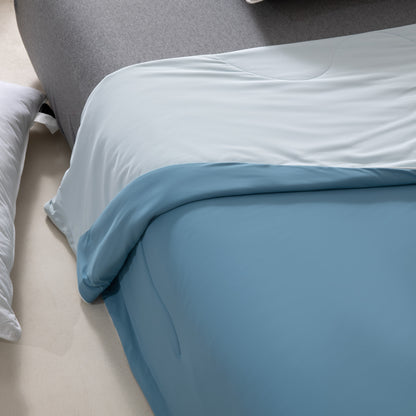 Close-up of a bed with blue bedding and gray headboard