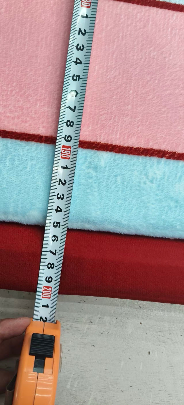 A close-up of a folded fabric or textile sample with horizontal pink, light blue, and red stripes, shown next to a measuring tape held by a hand.