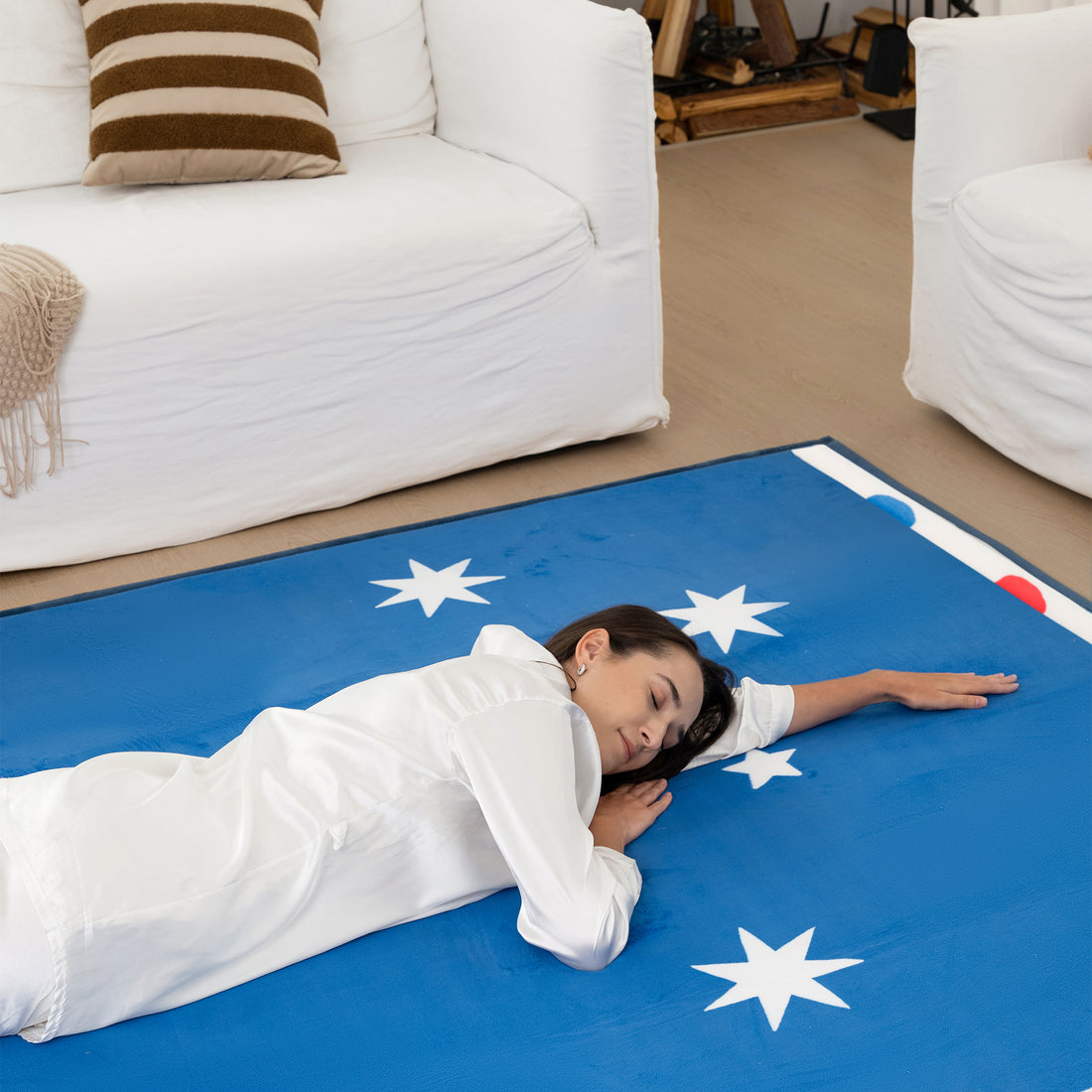Woman lying on a blue mat with white star patterns in a living room.