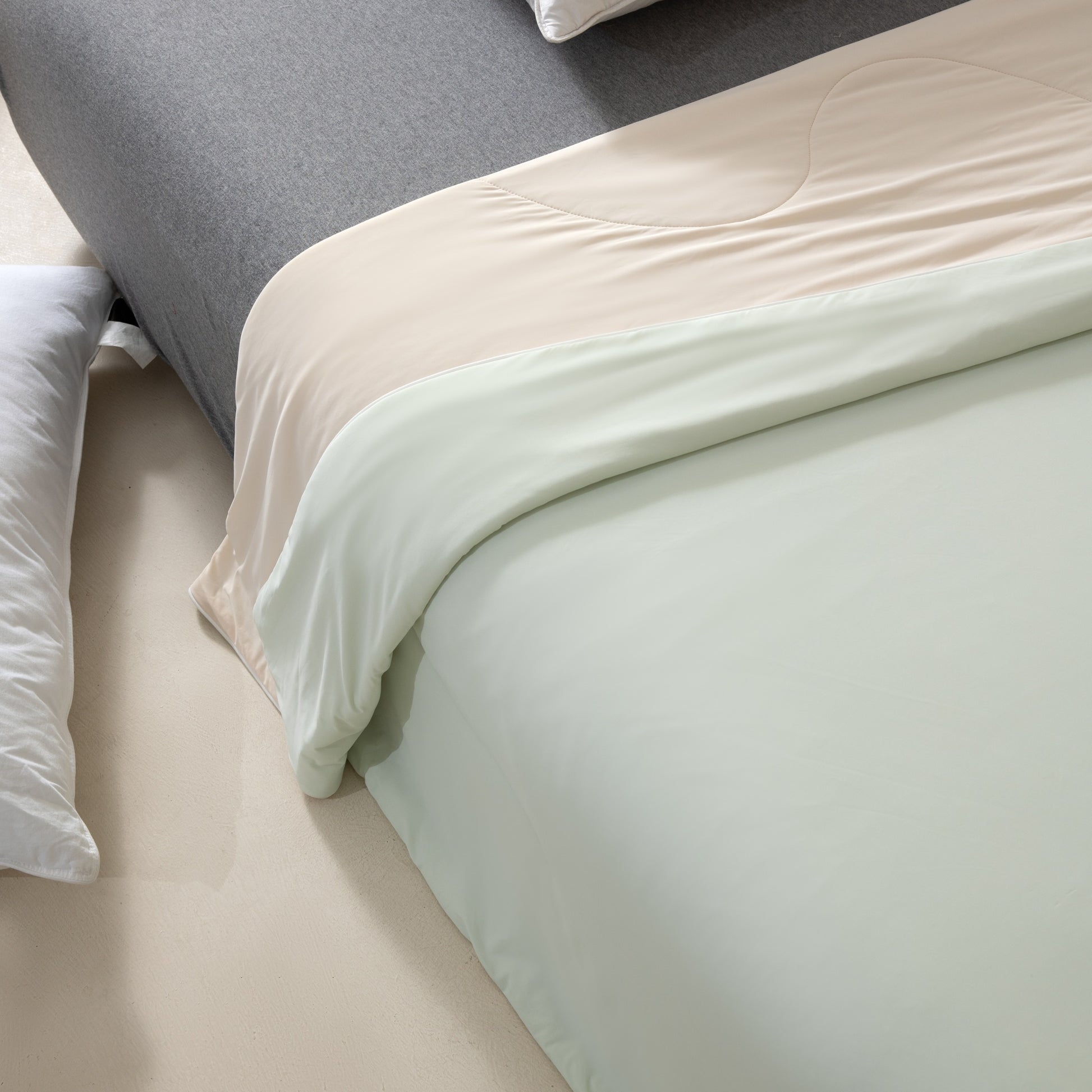 Close-up of a bed with light-colored bedding and pillows.