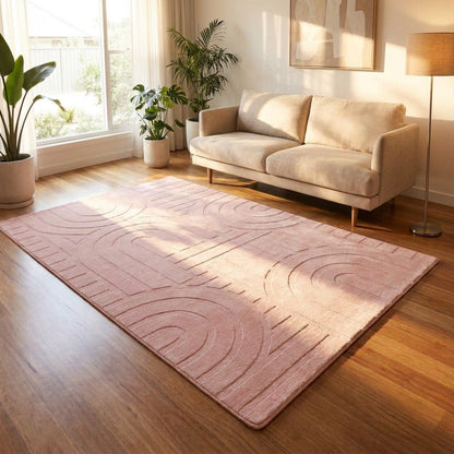 Living room with a pink rug, beige sofa, and plants.