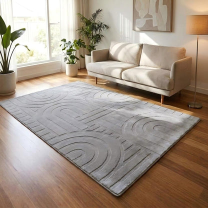 Gray textured rug on a wooden floor in a living room with a beige sofa and plants.