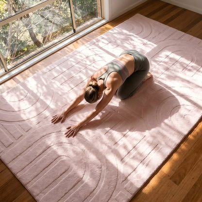 Person practicing yoga on a textured rug with natural light streaming through a window.