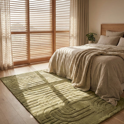 Bedroom with a green rug, bed, and large window with blinds.
