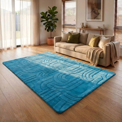Blue textured rug on a wooden floor in a living room with a beige sofa and decorative items.
