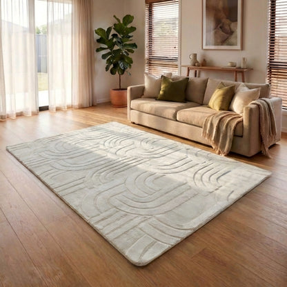 Living room with a beige sofa, decorative pillows, and a textured area rug on wooden flooring.