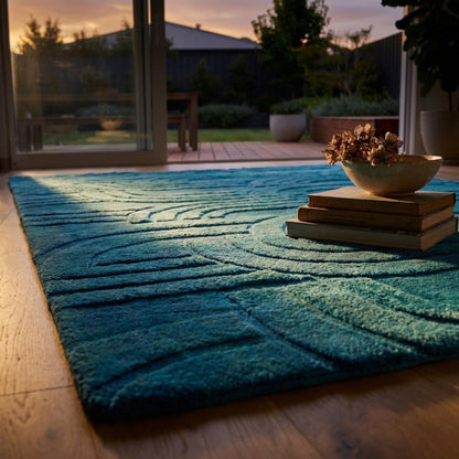 Blue textured rug on a wooden floor with a bowl and books in the foreground, and a garden view through a glass door in the background.