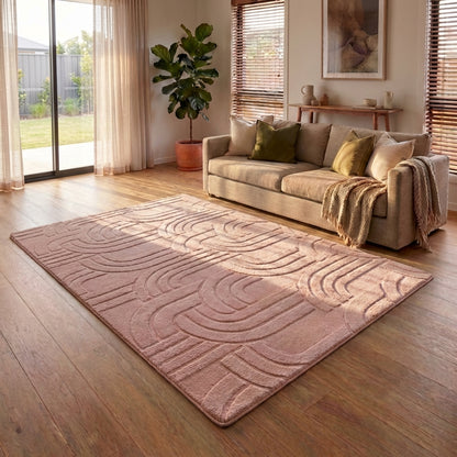 Living room with a textured pink rug, beige sofa, and decorative pillows.