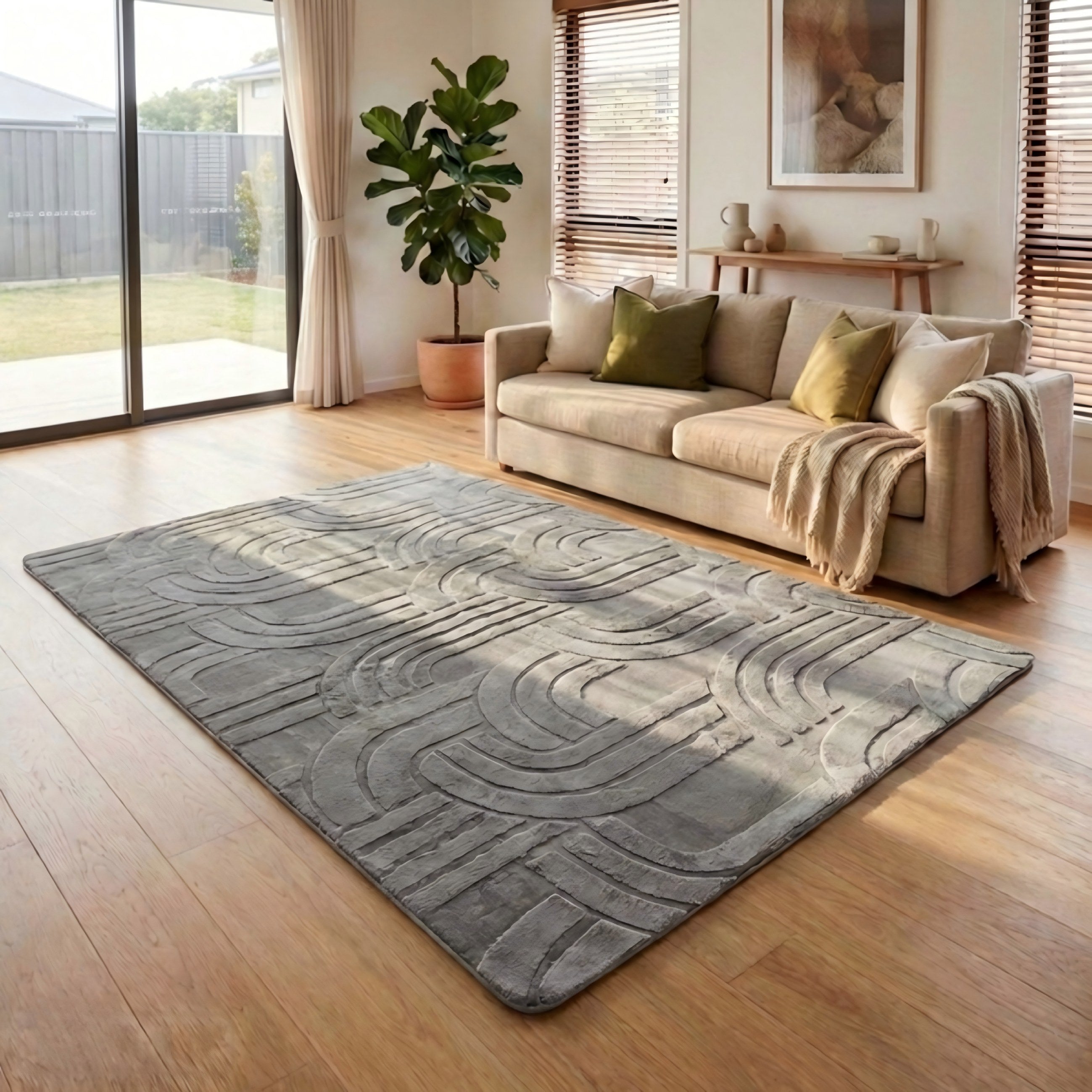 Living room with a gray patterned rug, beige sofa, and a plant.