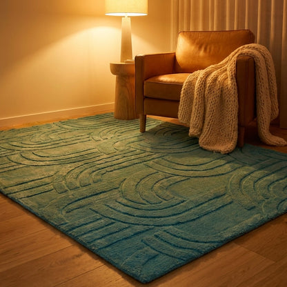 Brown leather armchair with a beige blanket on a blue textured rug in a room with a lamp and curtain.