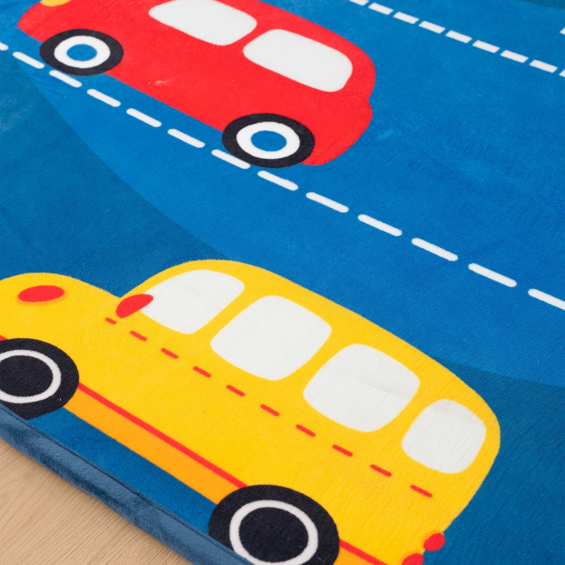 Children's play mat with red car and yellow school bus on a blue background