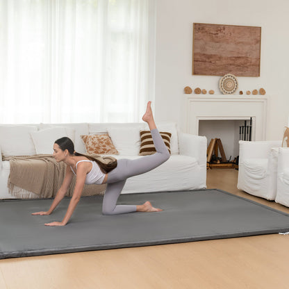 Woman practicing yoga on a mat in a living room.