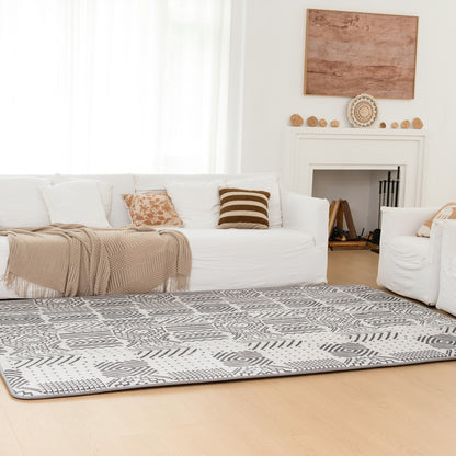 Living room with a white sofa, patterned rug, and fireplace.