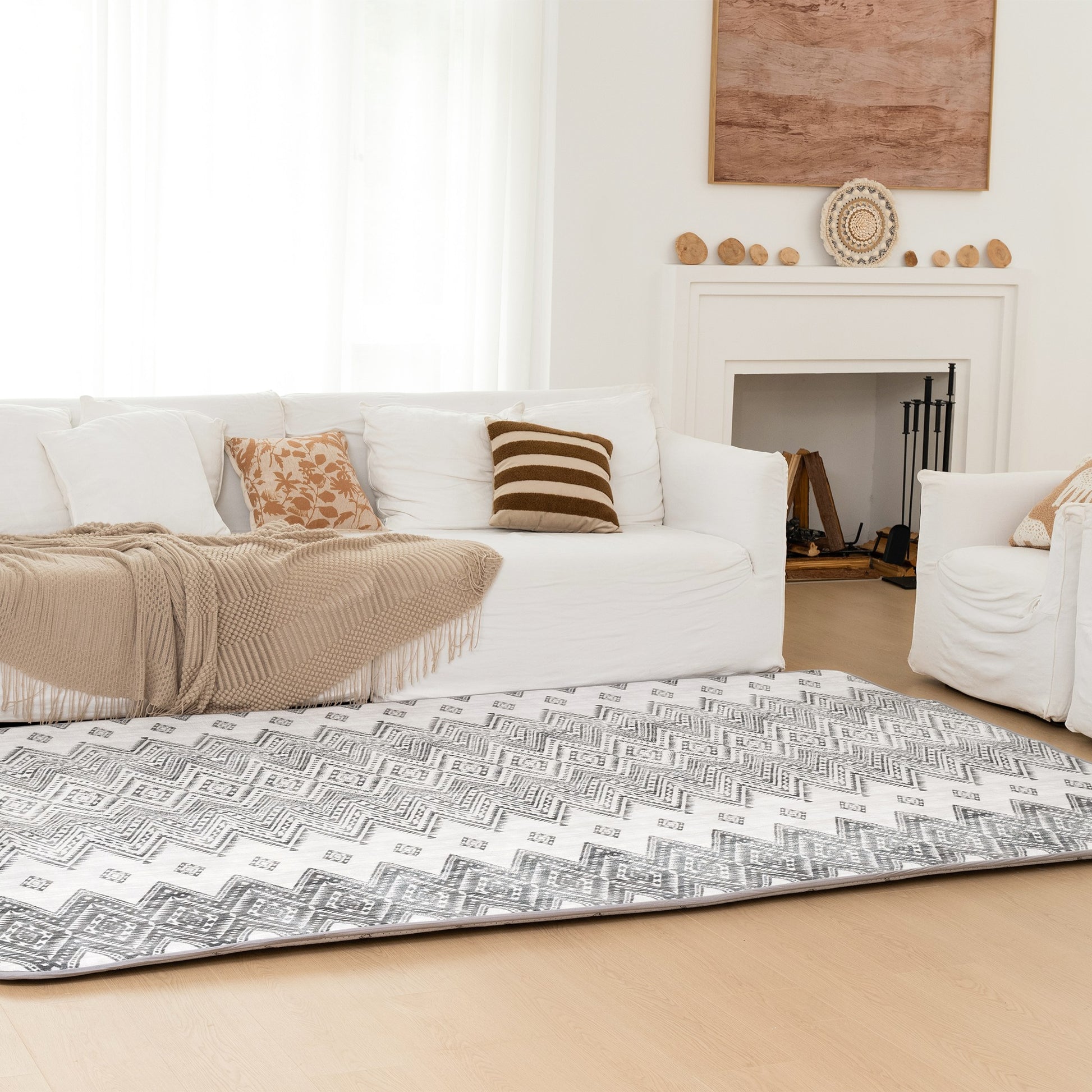 Living room with a patterned rug, a white sofa, and a fireplace.