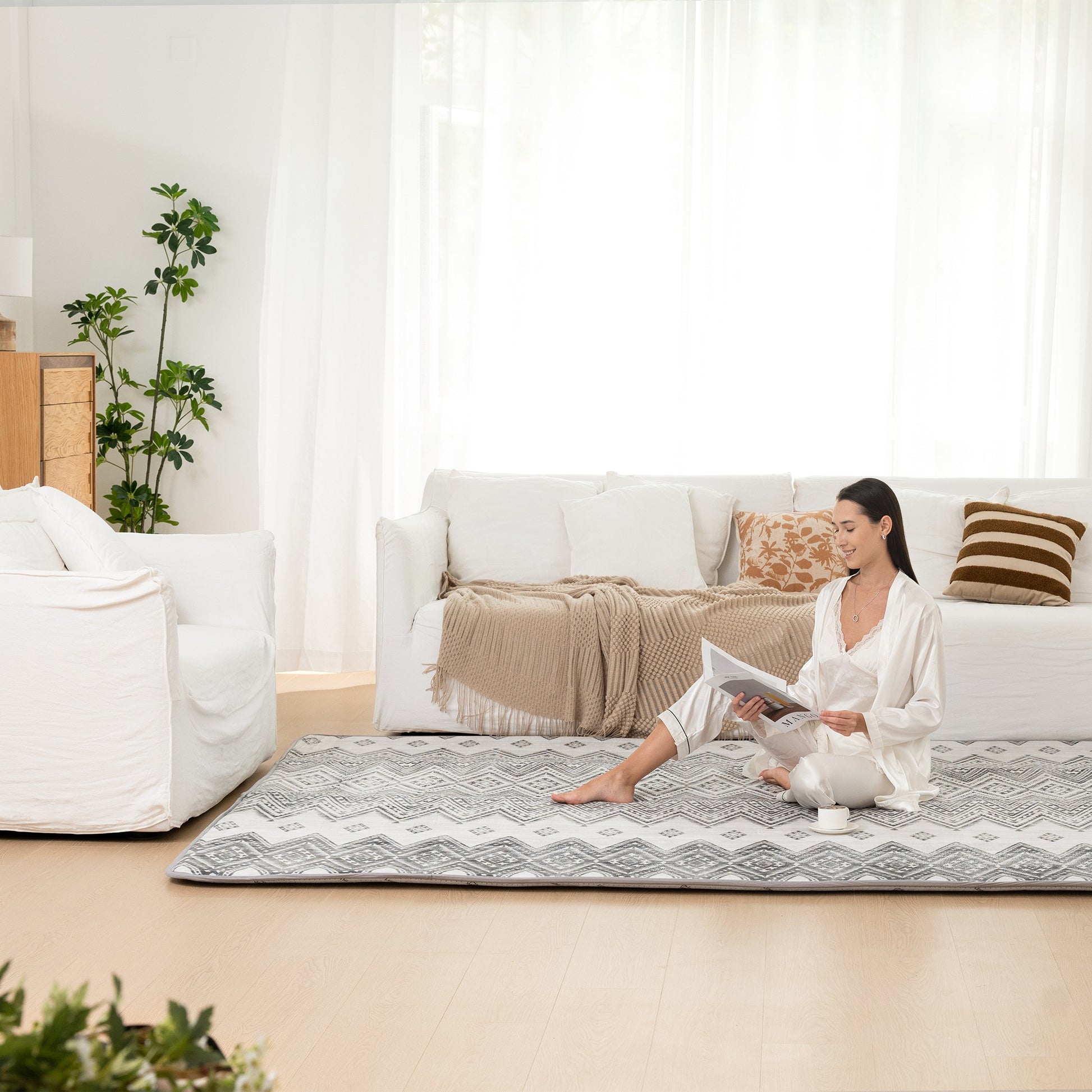 Woman reading a magazine on a patterned rug in a living room.