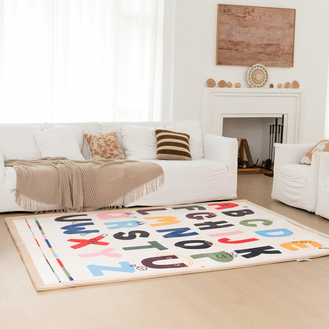 Living room with a white sofa, alphabet rug, and decorative items.