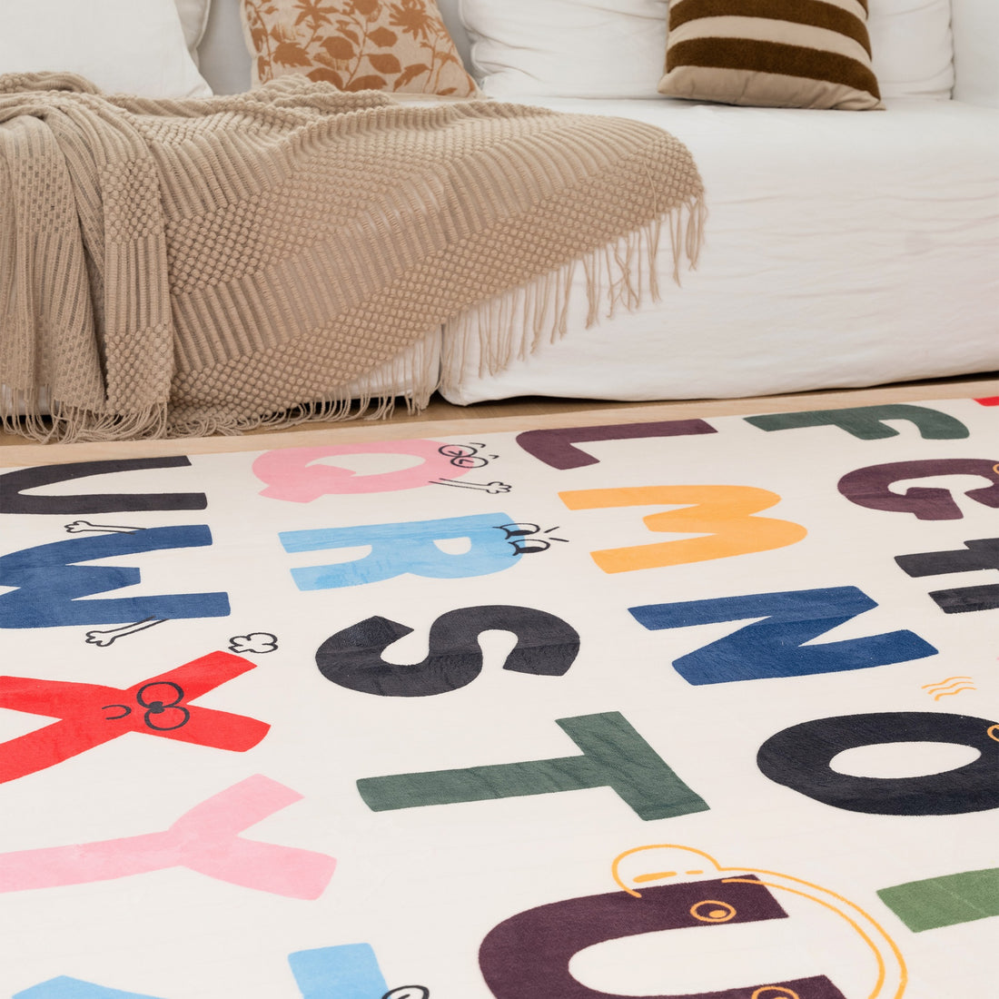 Living room with a white sofa, alphabet rug, and decorative items.