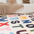 Colorful alphabet rug on a living room floor with a couch and pillows in the background.