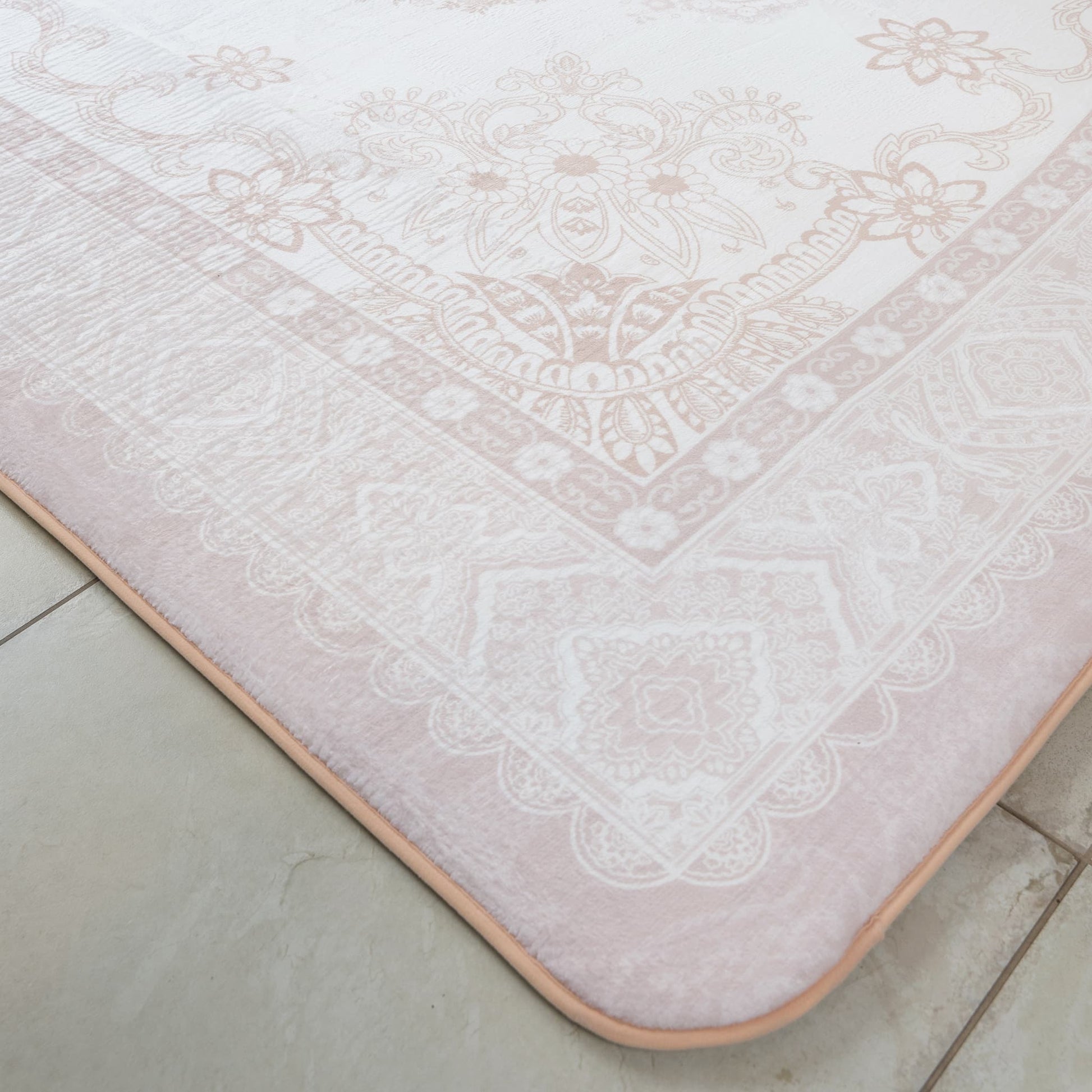 Patterned pink bath mat on a tiled floor