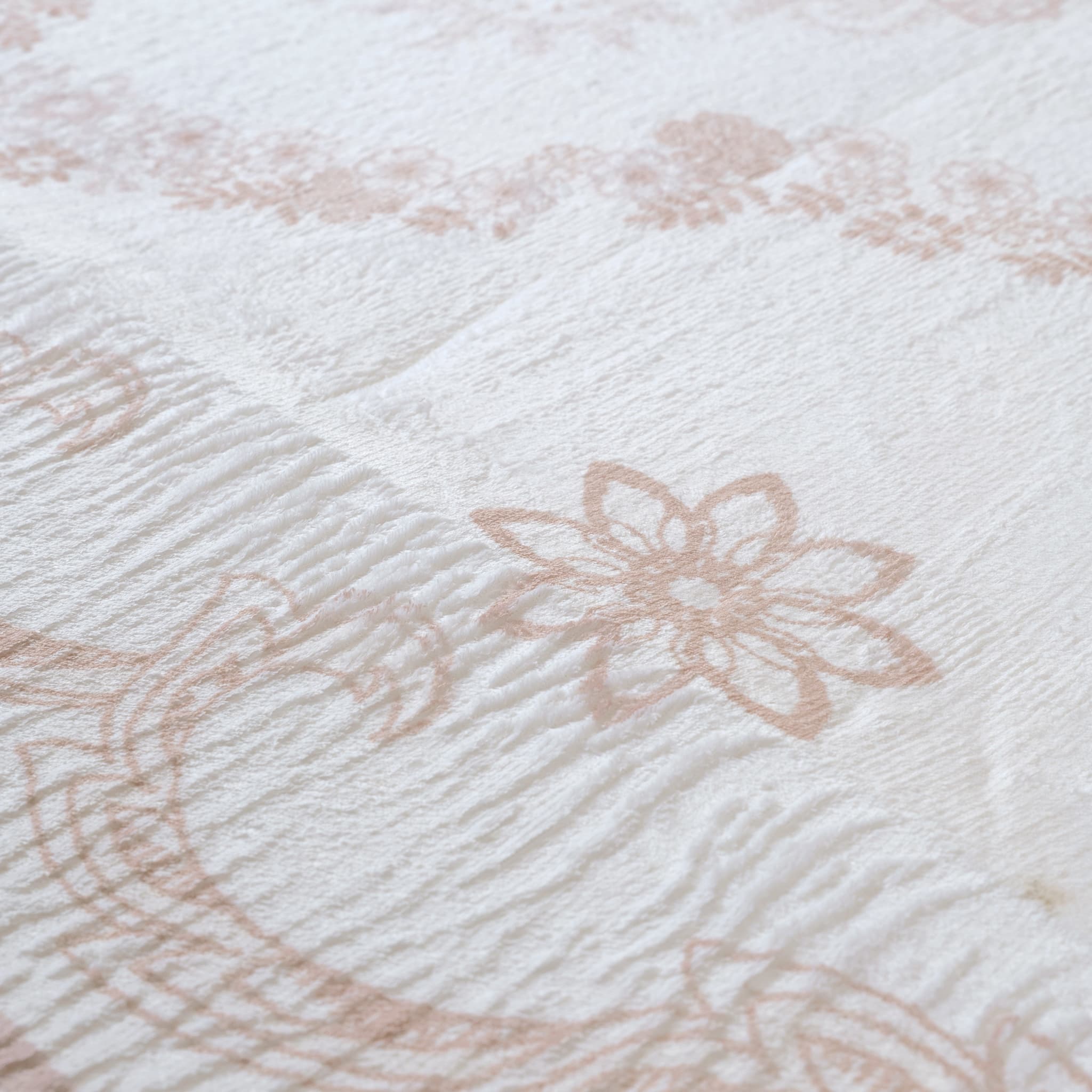Close-up of textured fabric with floral patterns in beige on a white background